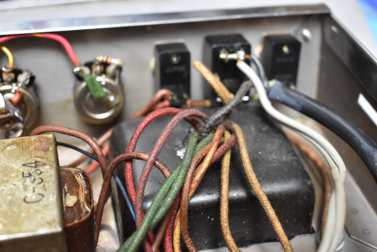 Close-up of the amp's internal wiring, showing a bundle of frayed, colorful cloth-covered wires and a transformer.