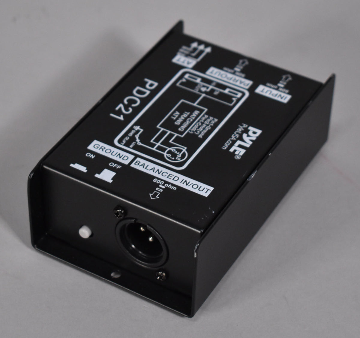 A black direct box, angled from above, shows a ground lift switch, an XLR input, and a circuit diagram on its top panel.