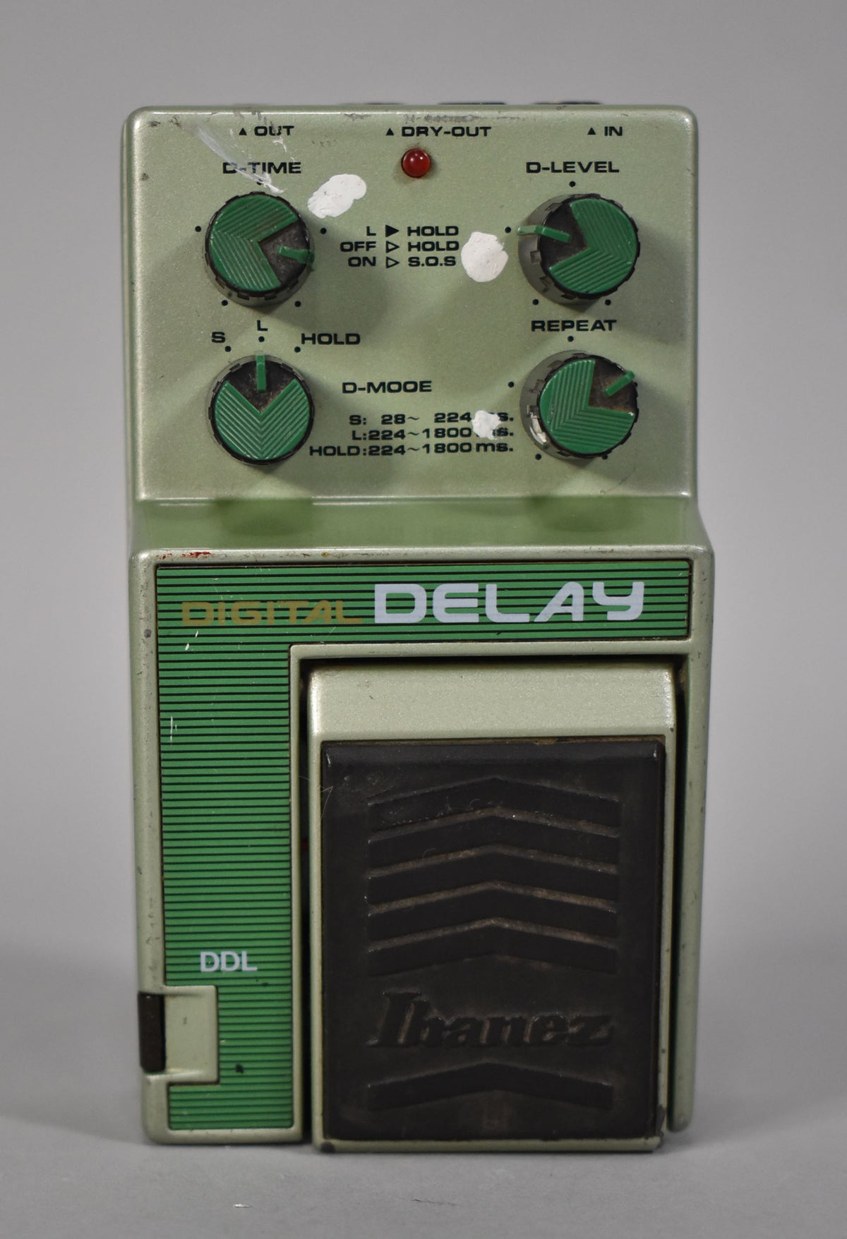 A top-down view of a pale green pedal with four dark green knobs, a red LED, and a black footpad.