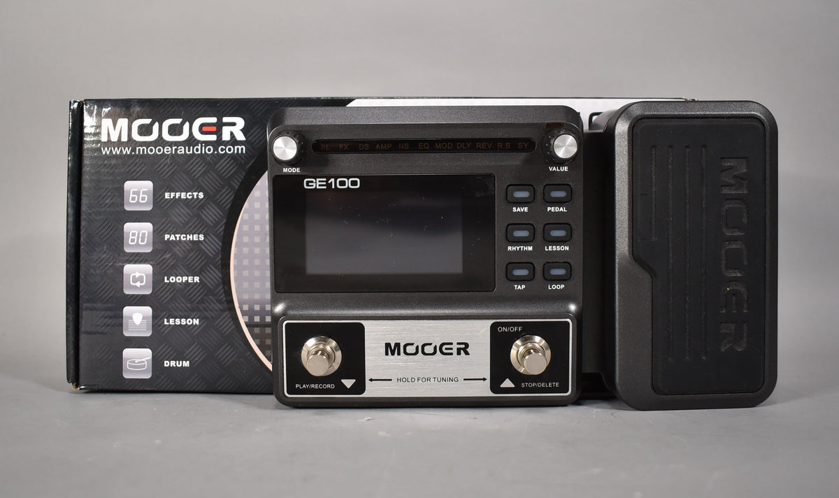 A dark grey multi-effects pedal with a large screen, two footswitches, and an expression pedal, shown with its box.
