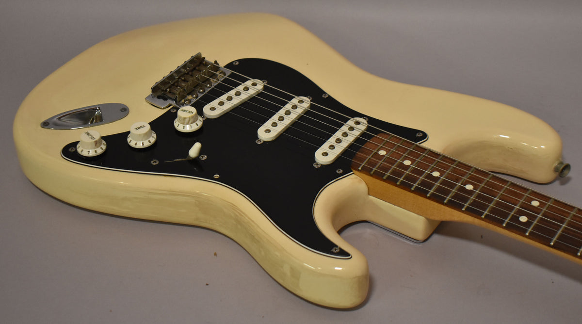 Cream-white Stratocaster body with a black pickguard, three single-coil pickups, and a maple neck with a rosewood fretboard.