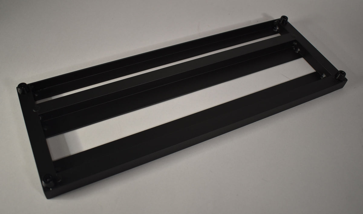 The black metal pedalboard is angled from the top right, showing its four horizontal slats and four adjustable feet.