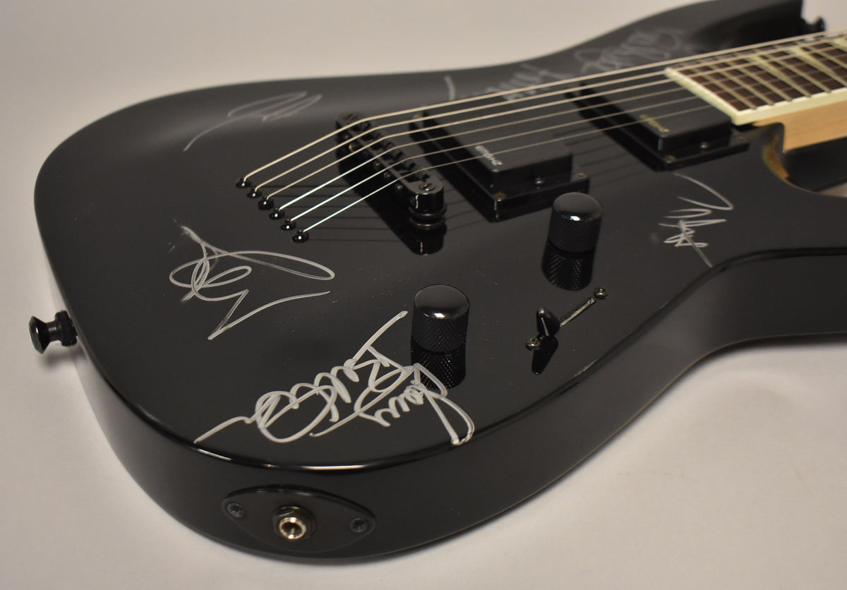 The upper body of a black satin electric guitar, angled from the lower bout, shows white signatures and black hardware.