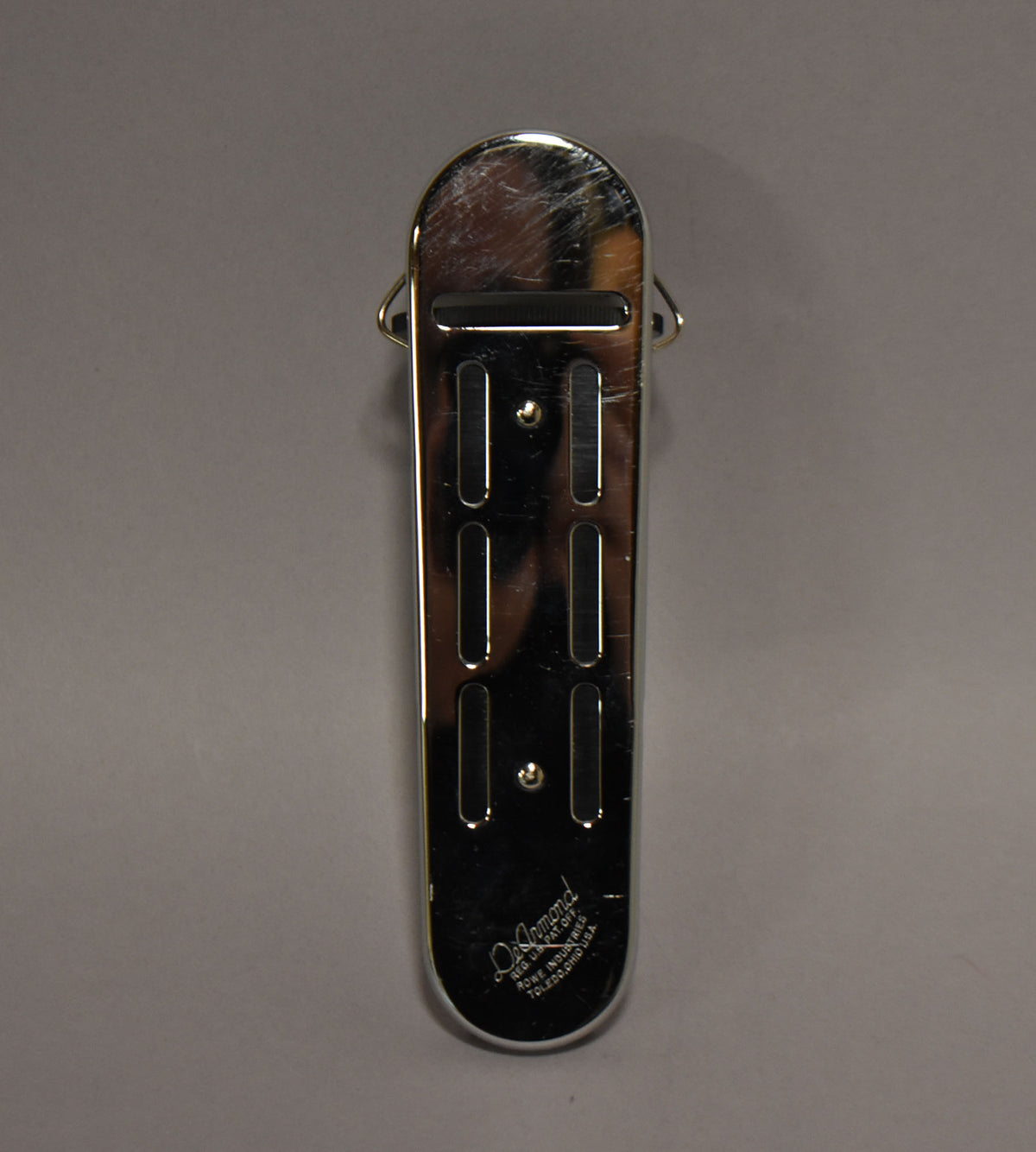 Top-down view of a chrome pickup with four rectangular pole piece slots and two mounting screws, showing surface scratches.