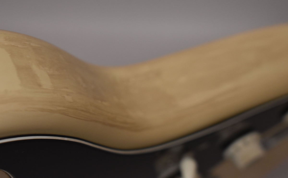 Close-up of the guitar's upper body, showing heavy discoloration and wear on the aged Arctic White finish, with a black pickguard.