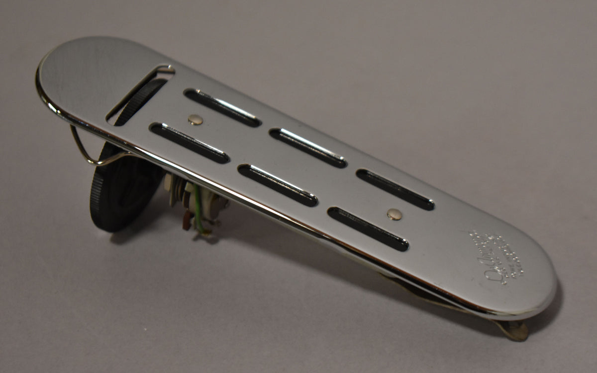 A chrome soundhole pickup, angled from the left, shows six black pole pieces, a black volume knob, and wiring.