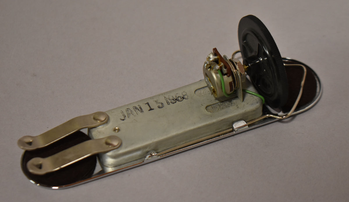 A chrome soundhole pickup, viewed from above and slightly to the right, showing the volume pot and black plastic knob.
