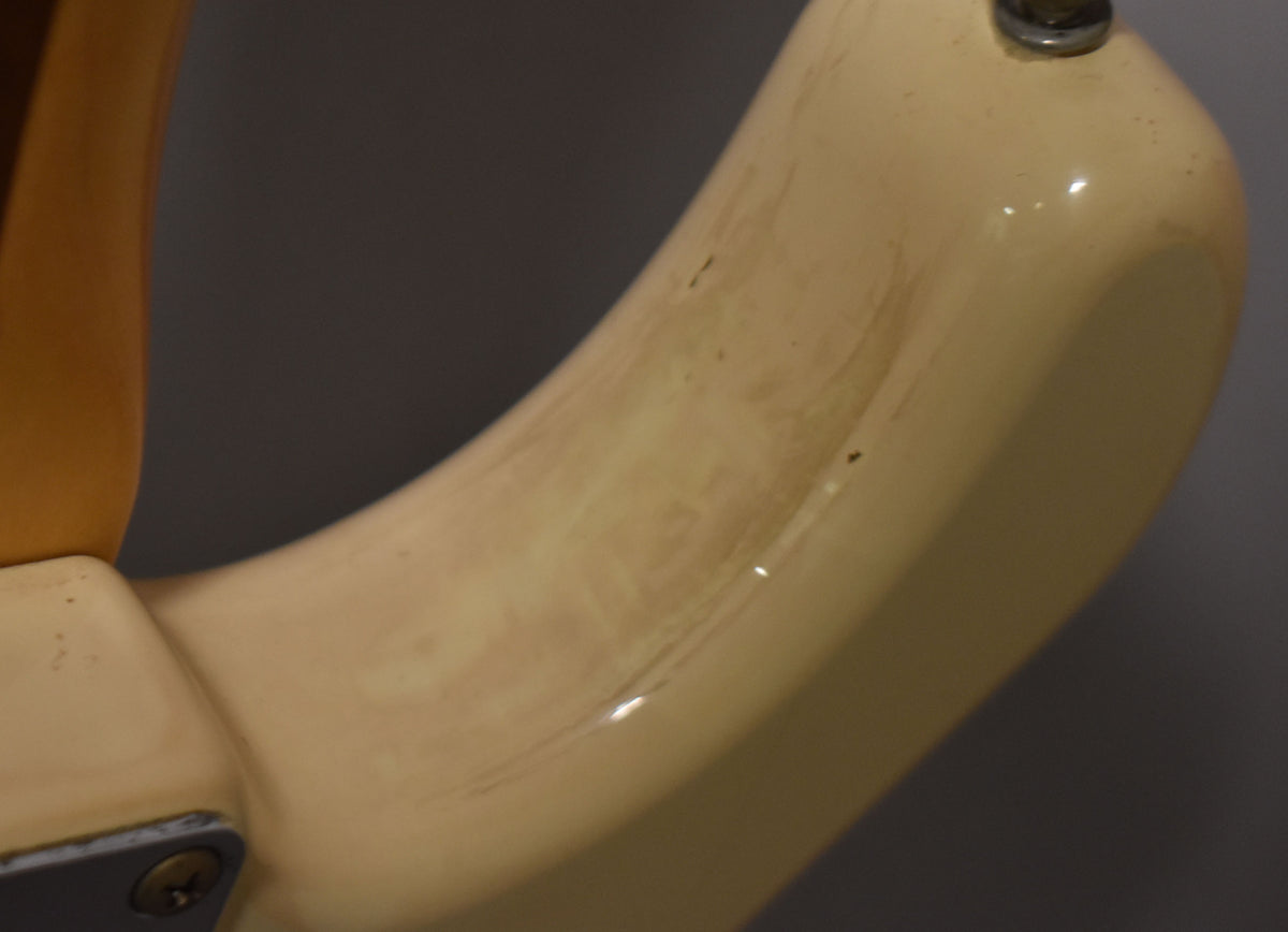 Close-up of the guitar's upper horn, showing a glossy, aged white finish with visible brown discoloration and small dark chips.
