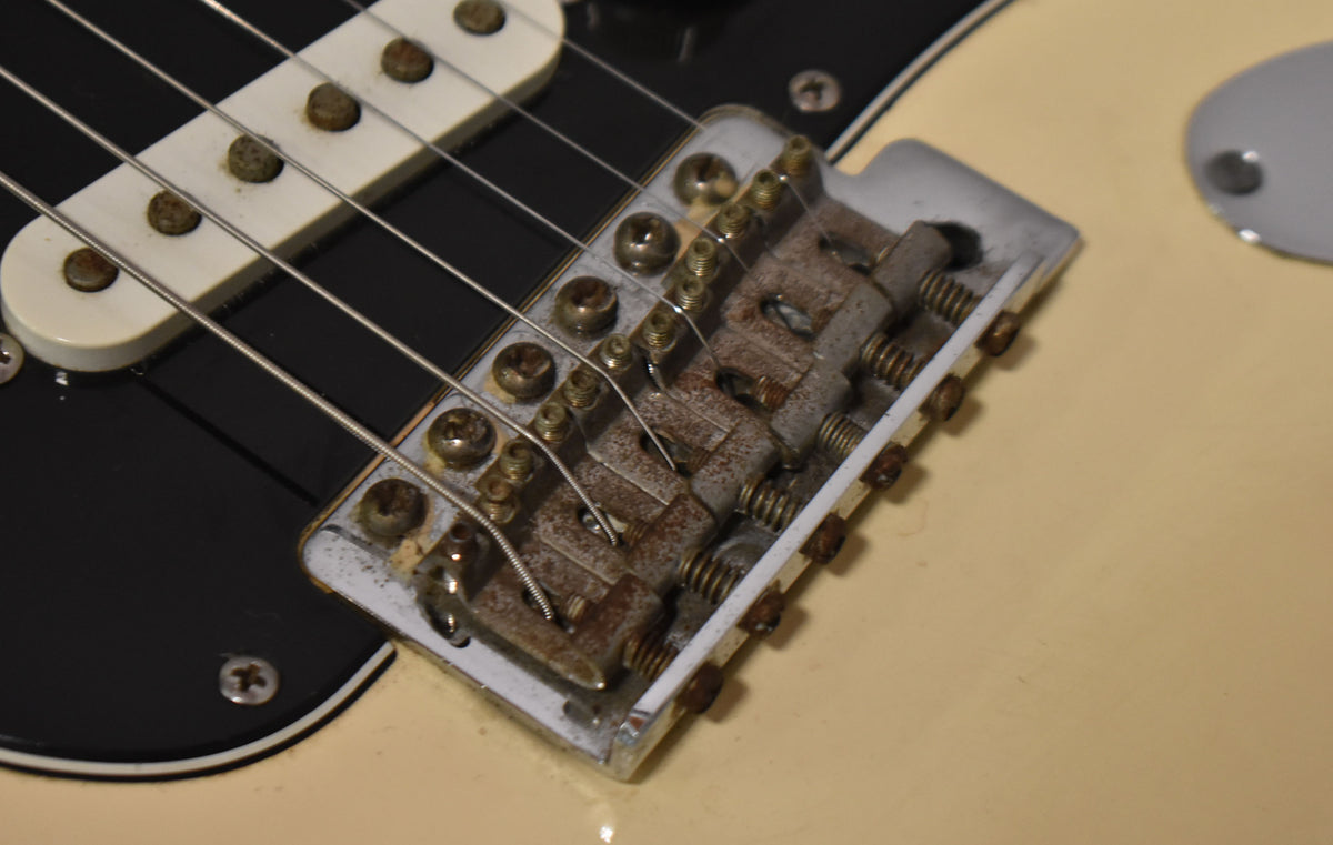 Close-up of the guitar's bridge and middle pickup, showing heavy rust on the bridge saddles and screws, and tarnished pole pieces.