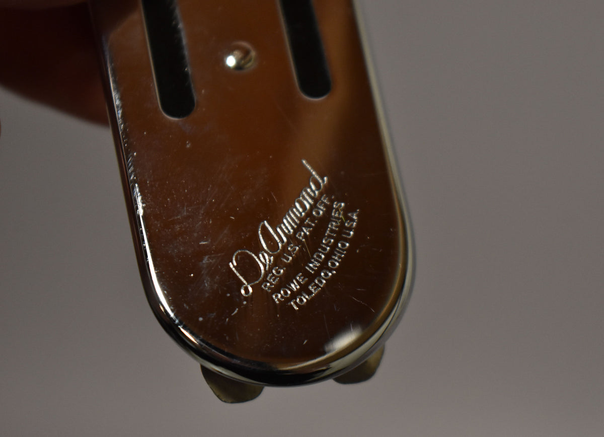 Close-up of the pickup's chrome underside, showing light scratches and a small mounting screw, with two brass feet visible.