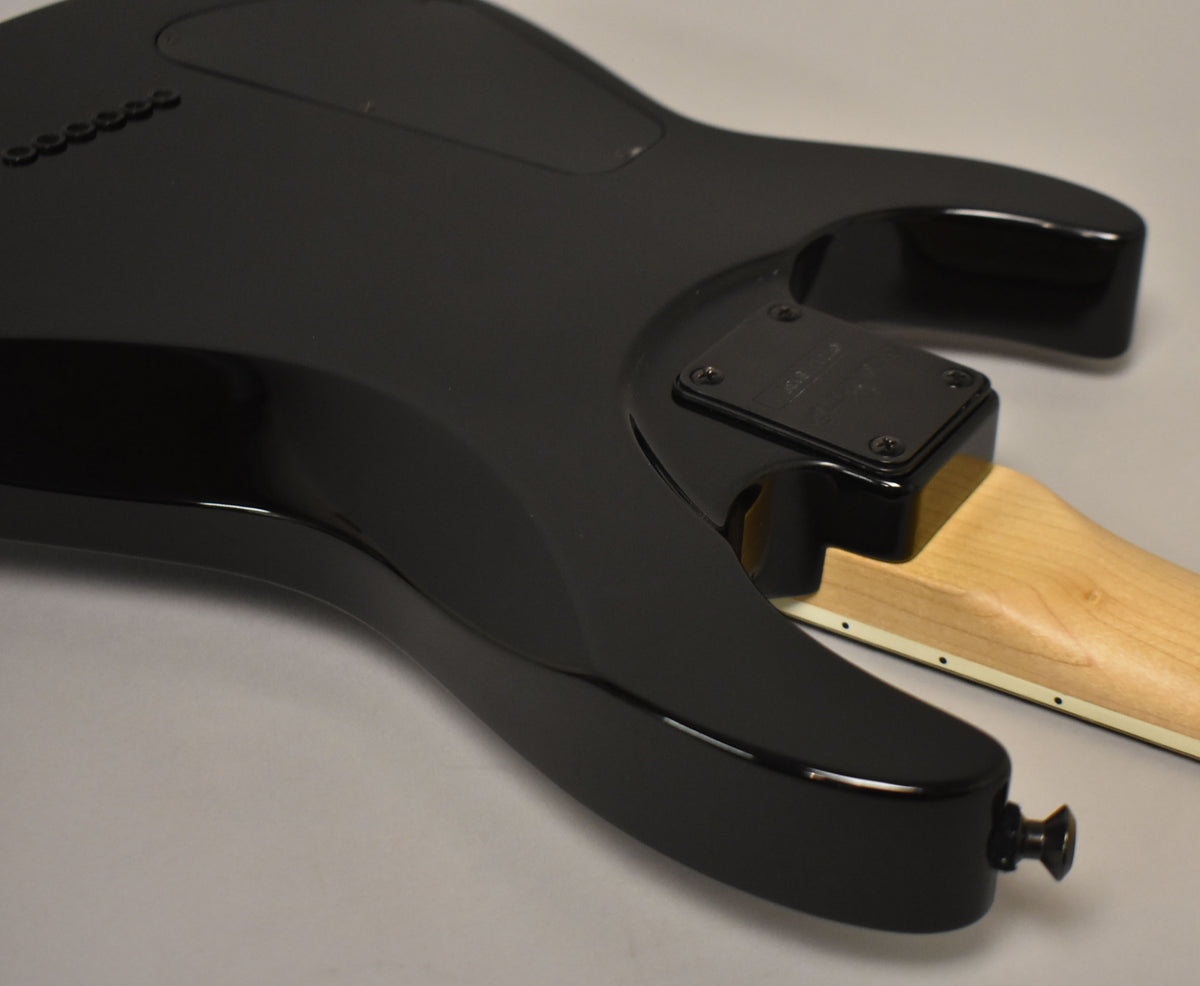 The guitar's glossy black body and neck joint are visible from the back, with a light wood neck and black strap button.