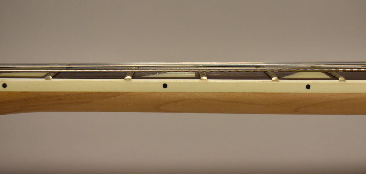 A close-up of the guitar's maple neck and dark fretboard, showing the frets, strings, and black side dot markers.