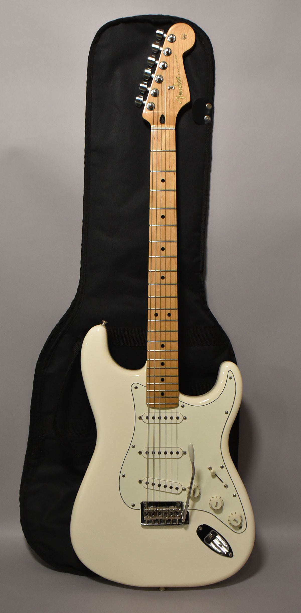 Full-length view of a polar white Stratocaster with a maple neck, white pickguard, three single-coil pickups, and a tremolo arm.