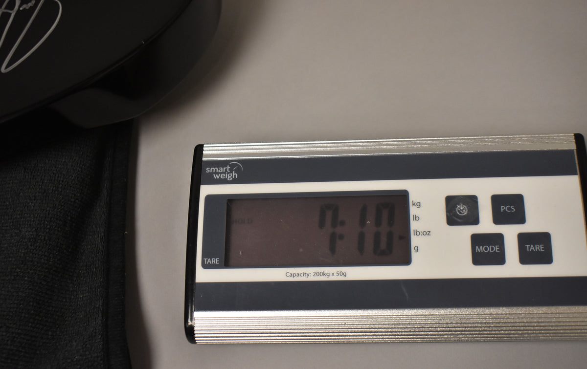 A Smart Weigh digital scale displays "7.10" in kilograms and "7.10-" in pounds/ounces, with a black guitar case partially visible.