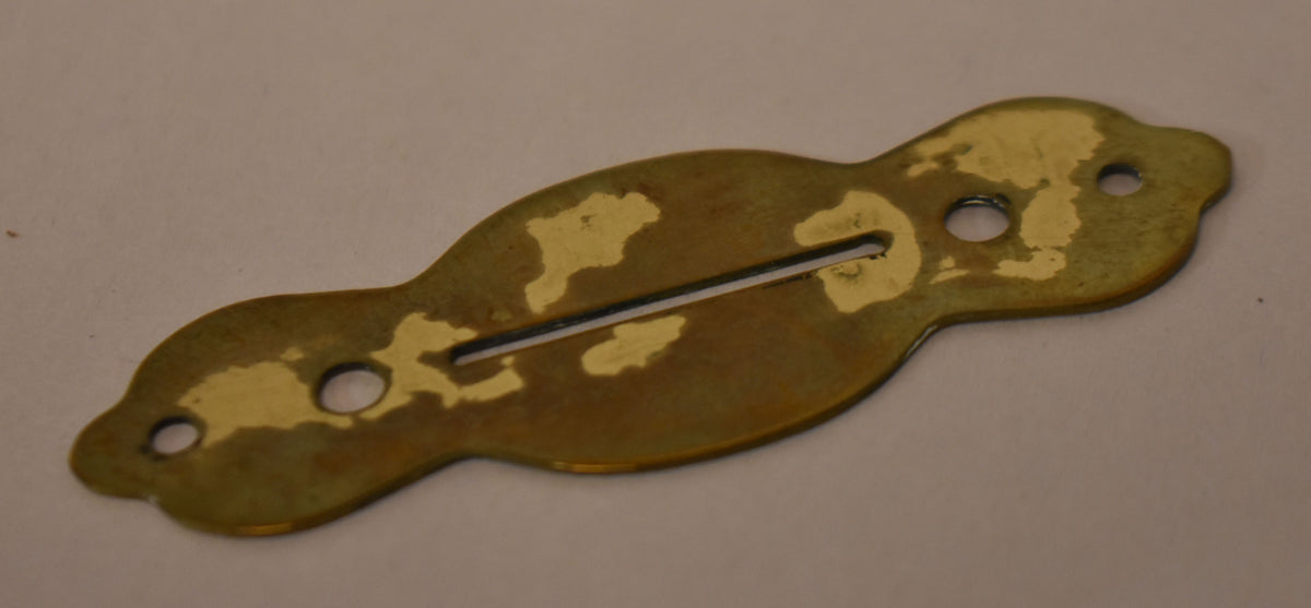 Gold brass selector switch plate, viewed from above, with a long slot and three screw holes, showing significant finish wear.