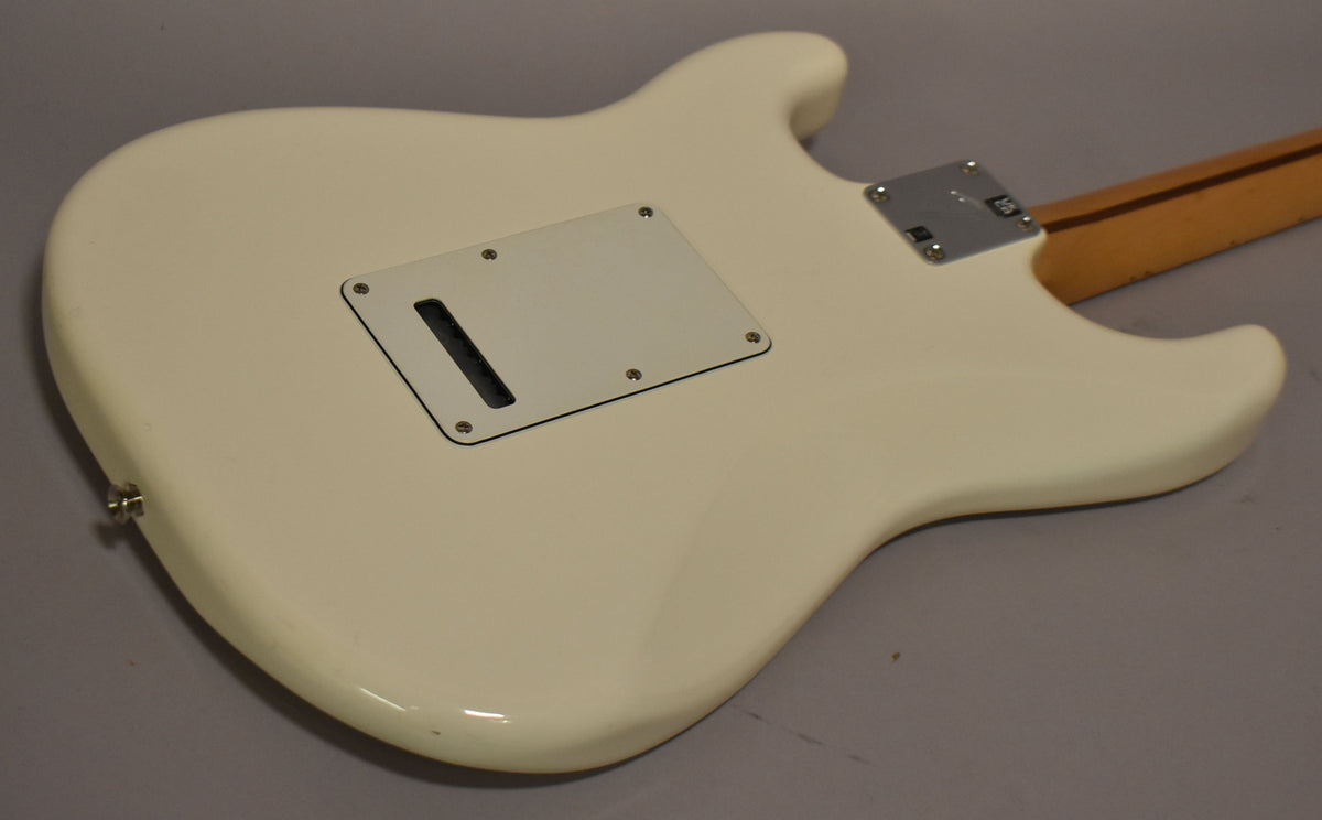 The back of a polar white Stratocaster body, showing the tremolo cavity cover, neck plate, and strap button, with minor scuffs.