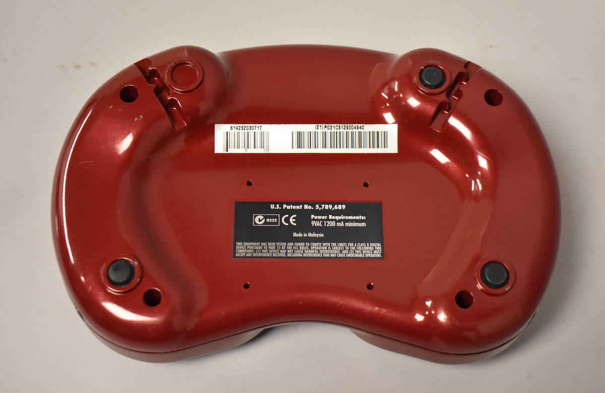 The red, kidney-bean-shaped pedal is shown from the back, revealing four black rubber feet and a central label with text and barcodes.