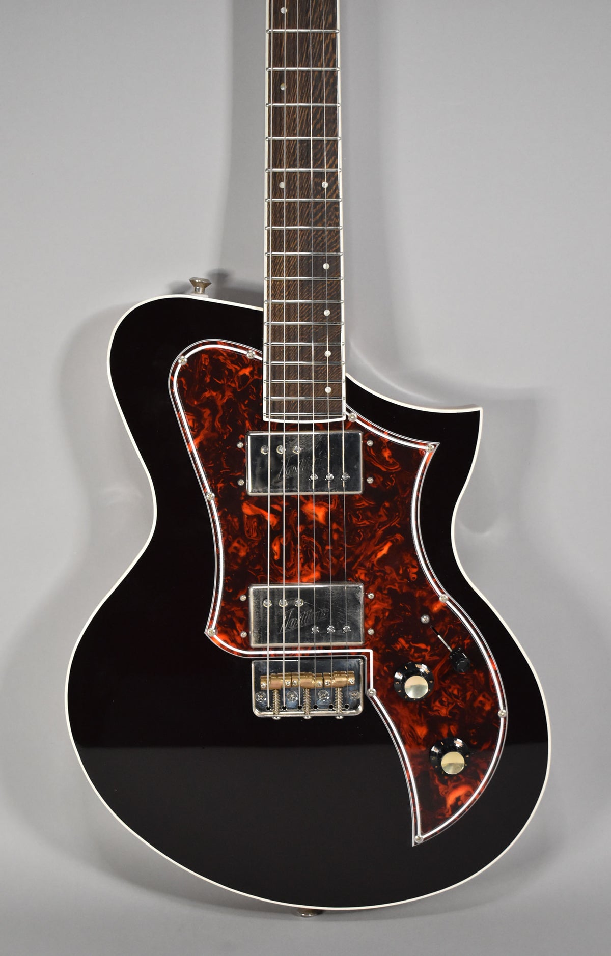 The Korona's oxblood body with white binding is framed from the neck to the lower bout, showing a tortoiseshell pickguard, two humbuckers, and two control knobs.