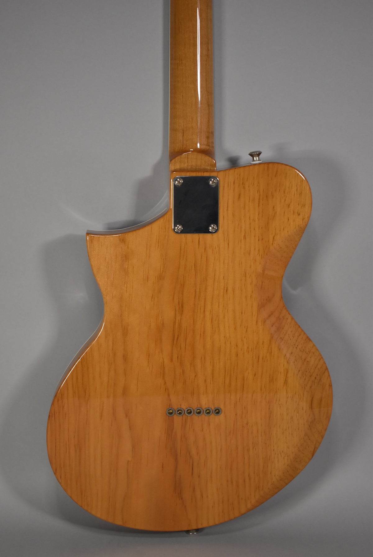 The back of the guitar shows a natural wood grain body with a glossy finish, a bolt-on neck, and six string ferrules.