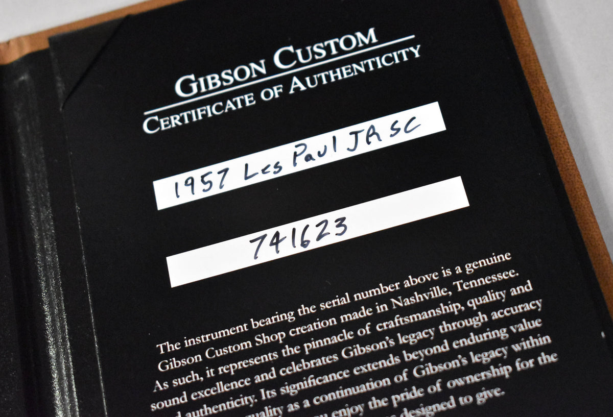 Close-up of the guitar's Certificate of Authenticity, showing "1957 Les Paul JA SC" and "741623" handwritten on white labels.