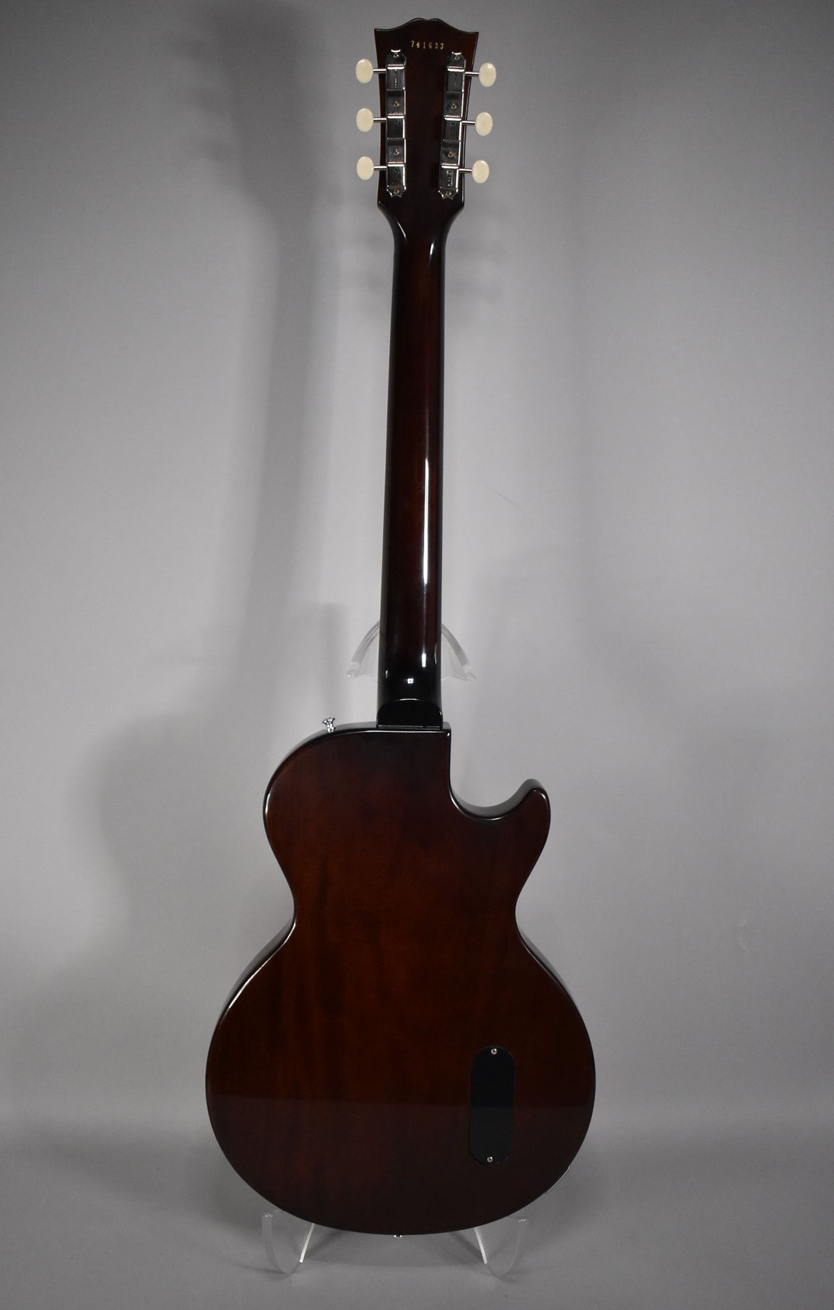 Full rear view of a dark brown guitar with a glossy finish, showing the headstock with six cream tuners and a black control plate.