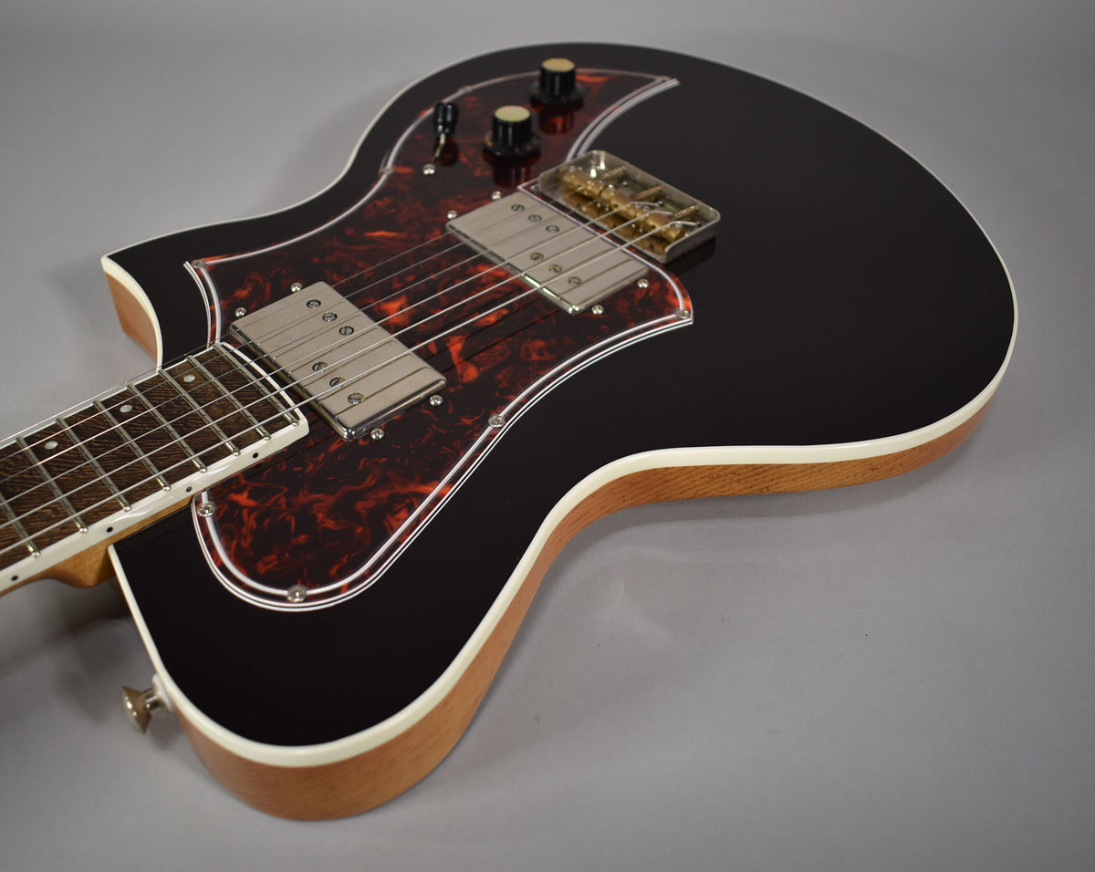 Oxblood electric guitar, angled from above, showing the glossy body, tortoiseshell pickguard, and two chrome humbuckers.