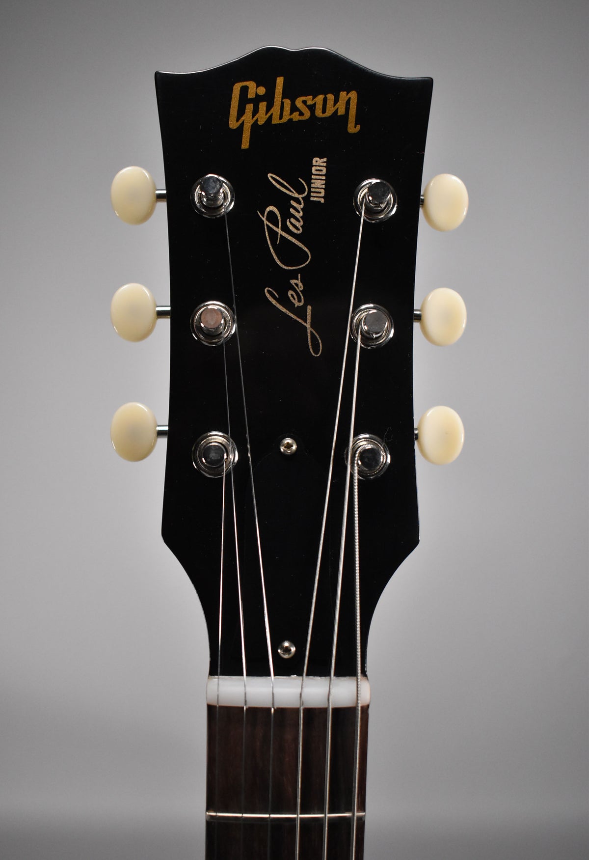The black headstock, with six cream tuning pegs and chrome hardware, is framed from the nut upwards.
