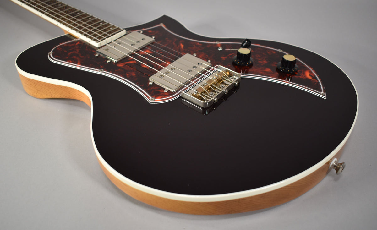 The oxblood guitar's glossy body, with a tortoiseshell pickguard, two chrome humbuckers, and two black knobs, is framed from the upper left.