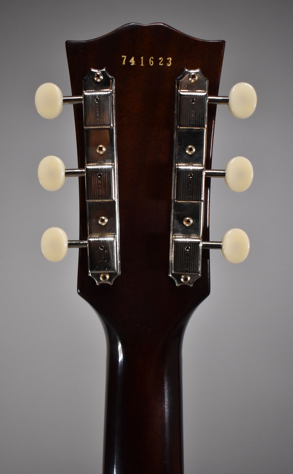 Rear view of the dark brown headstock and upper neck, showing six cream tuning pegs and chrome tuners.