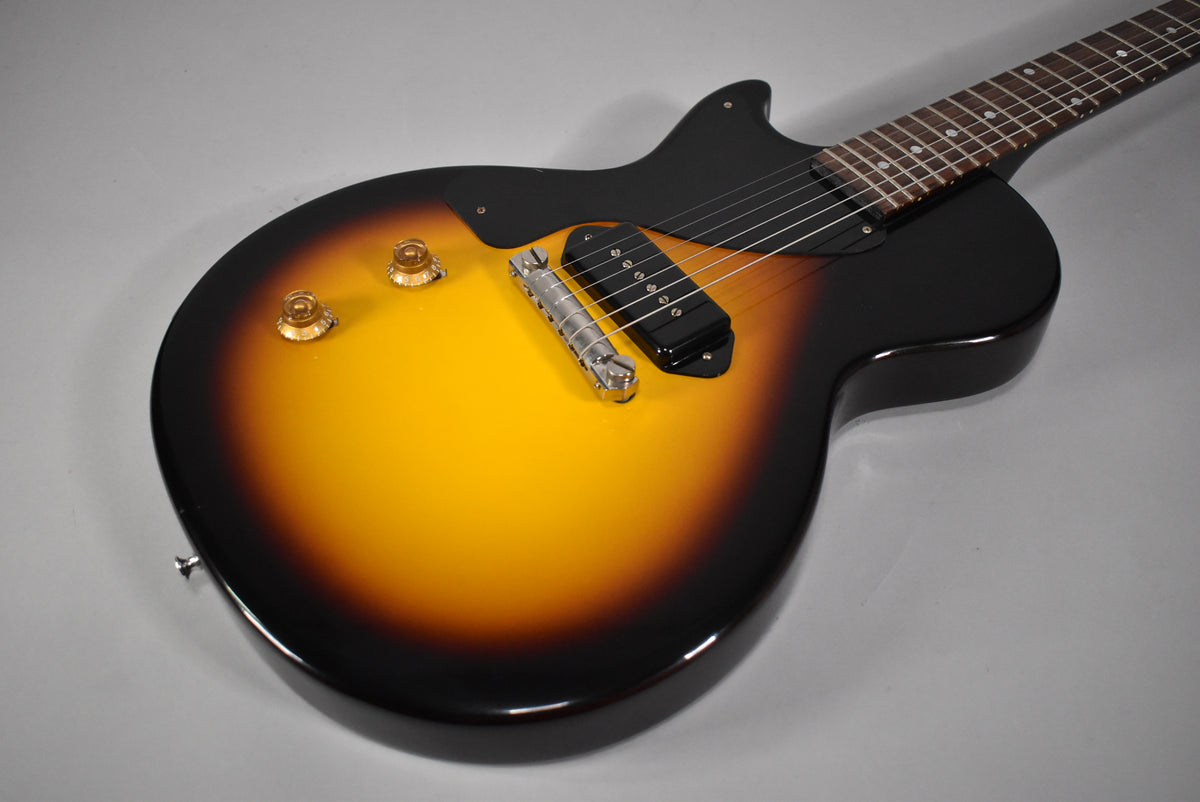 Left-handed sunburst Les Paul Junior, angled from the lower bout, showing two gold top hat knobs, a chrome wraparound bridge, and a black P90 pickup.