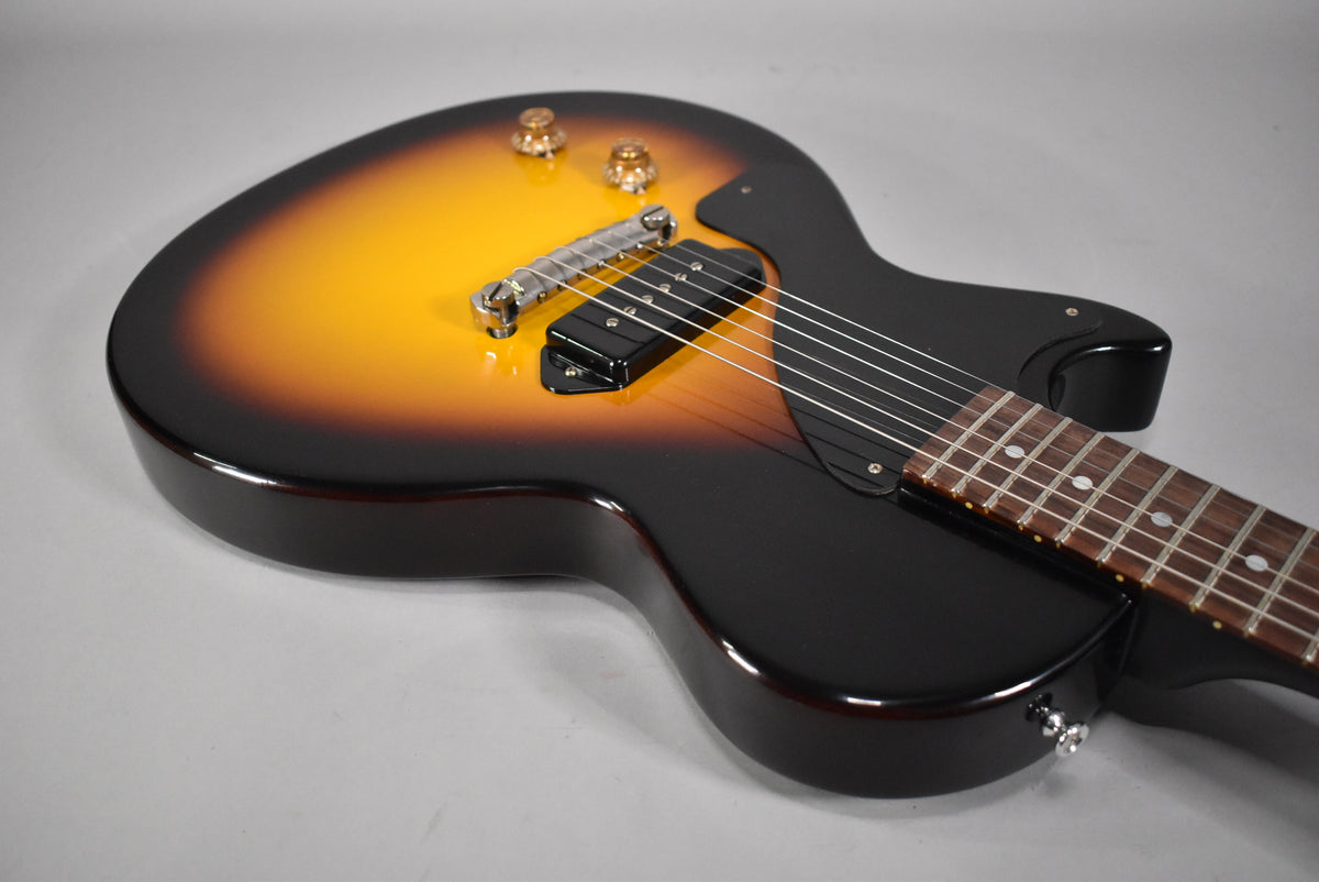 The left-handed sunburst guitar body, with a single P90 pickup and chrome bridge, is angled from the lower right.