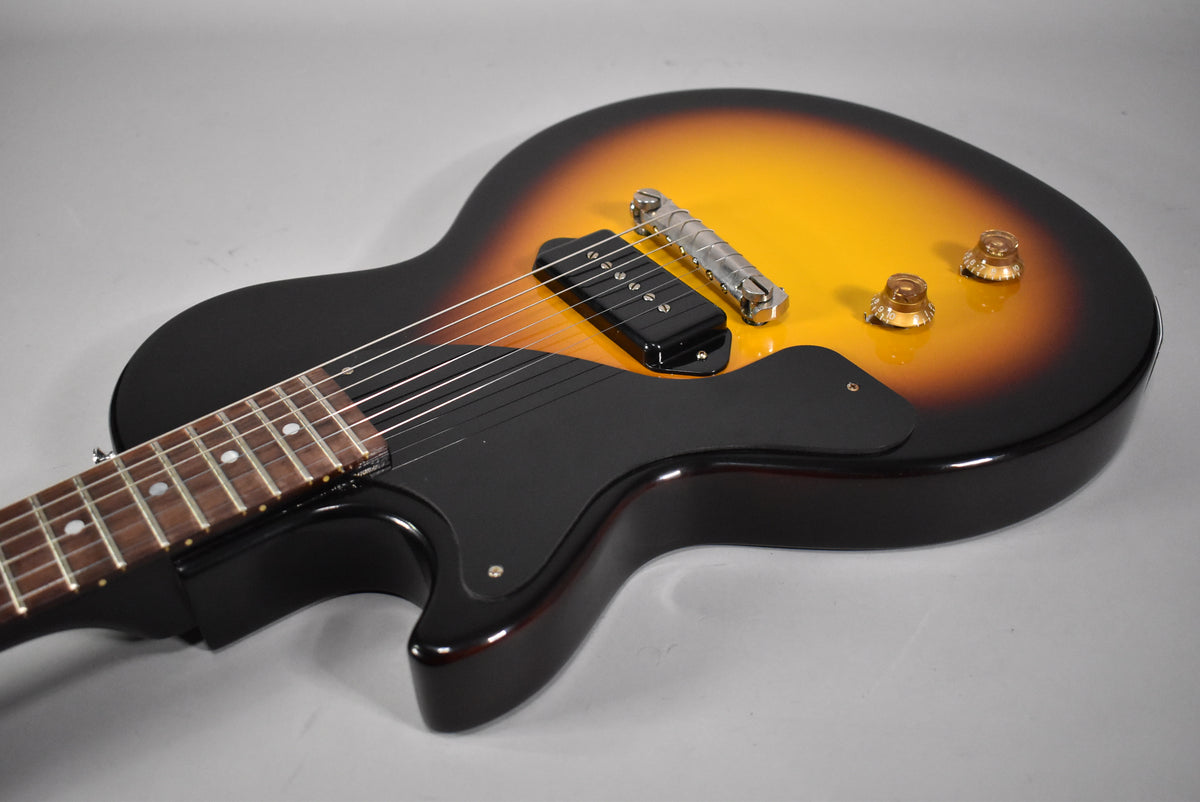 The sunburst Les Paul Junior's body is angled, showing its single P90 pickup, wraparound bridge, black pickguard, and two amber knobs.