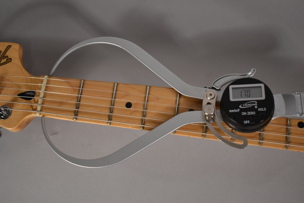 Close-up of the maple fretboard with a digital caliper measuring the fret height at 1.70mm, showing light wear on the frets.