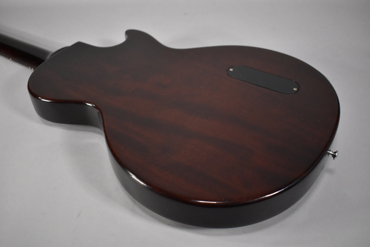 The guitar's dark sunburst back, with visible wood grain, features a black control cavity cover and a chrome strap button.