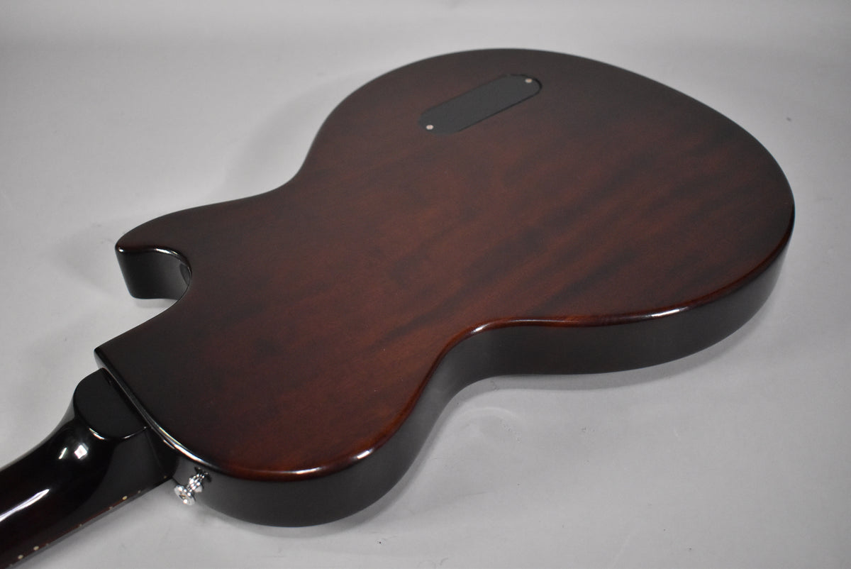 The back of the guitar, angled from the lower left, shows a dark reddish-brown body with a black control cavity cover and a chrome strap button.