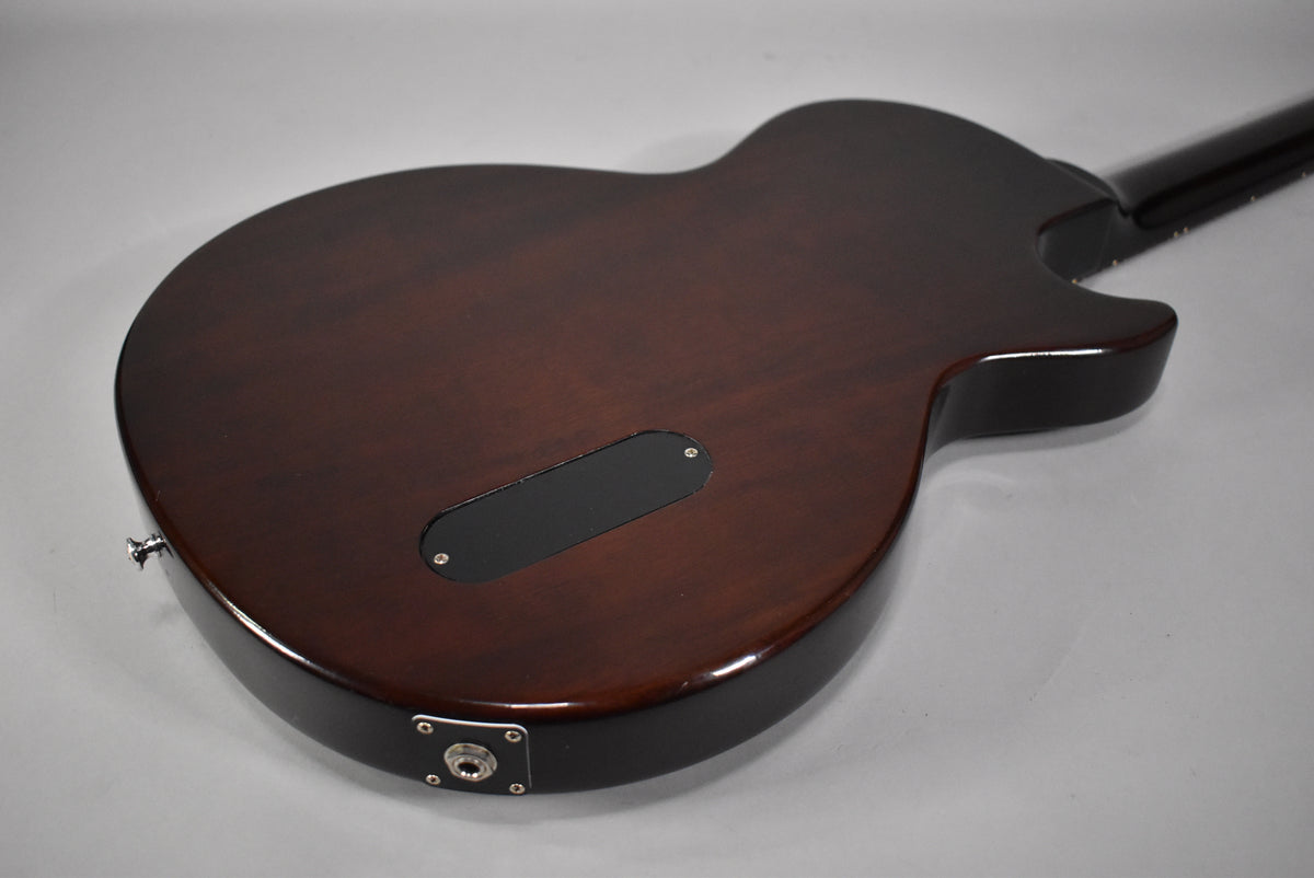 The back of a dark vintage sunburst guitar, showing a black control cavity cover and a chrome output jack.