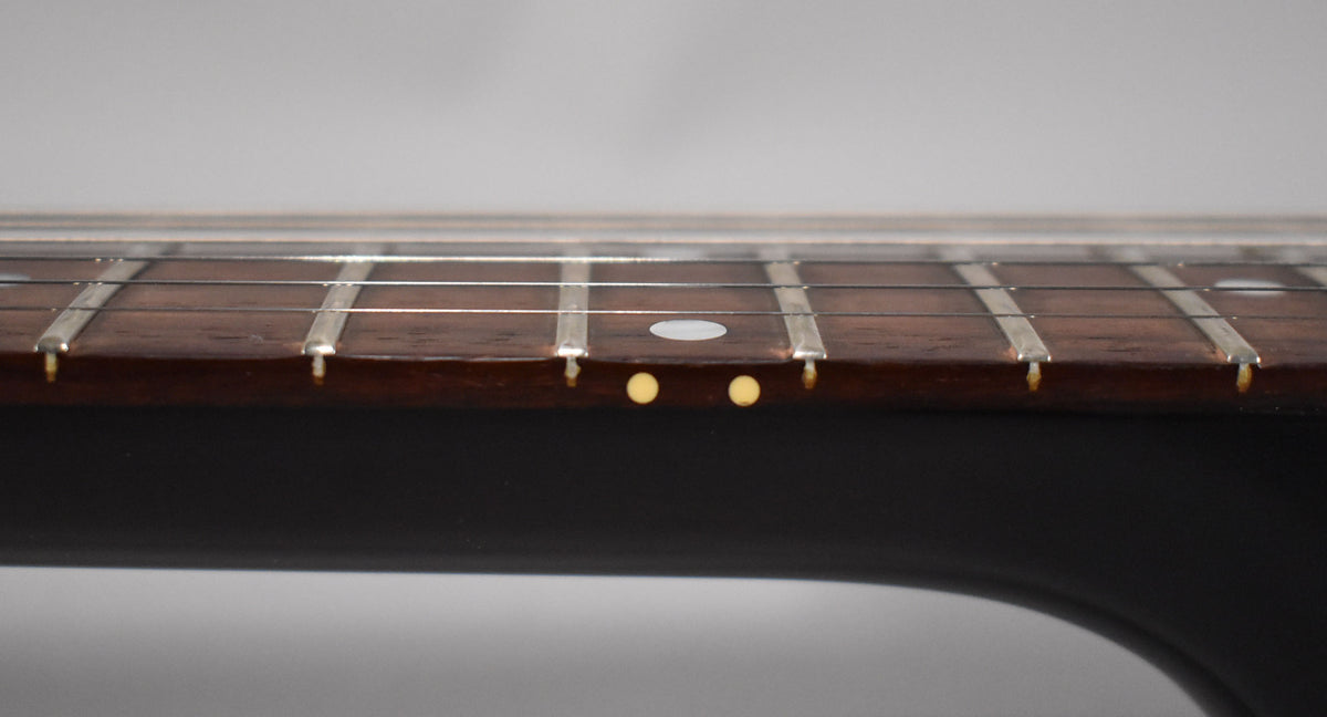 Close-up of the dark rosewood fretboard with a white dot inlay at the 7th fret and two yellow side dots.