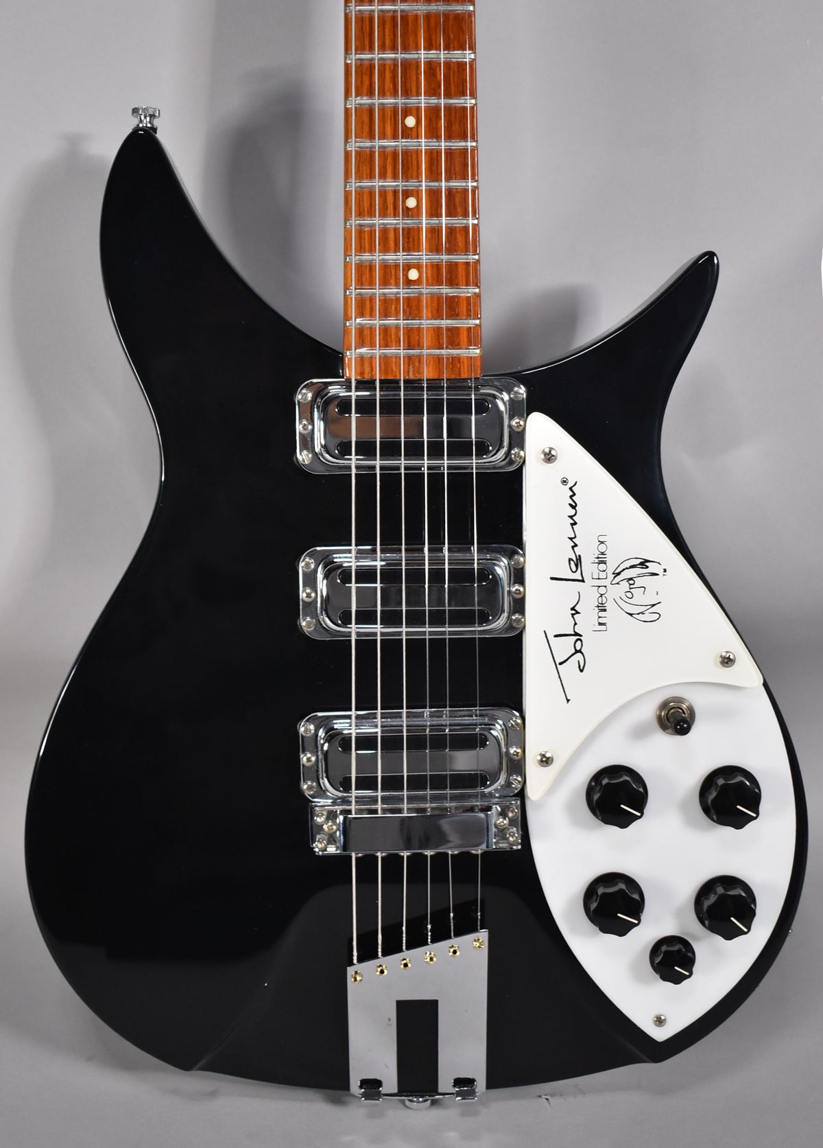 A black electric guitar with a white pickguard and five black control knobs, showing the body and lower neck.