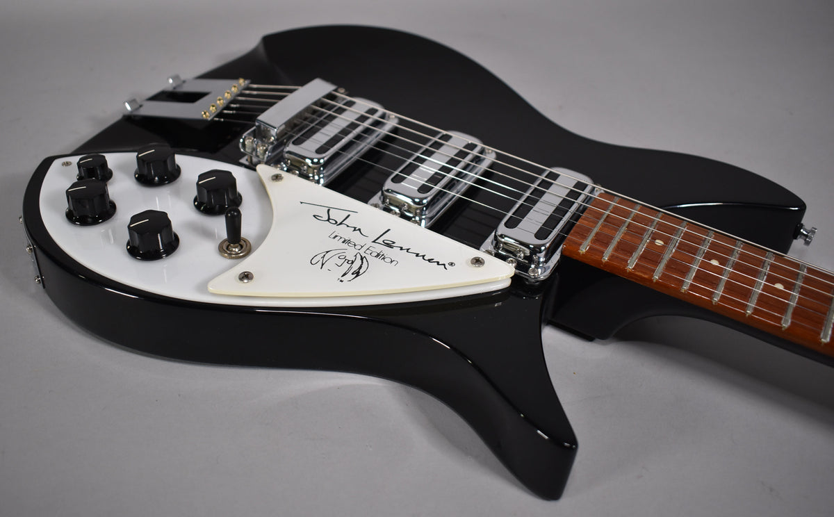Close-up of the glossy black body, white pickguard with signature, five black control knobs, and three chrome pickups.