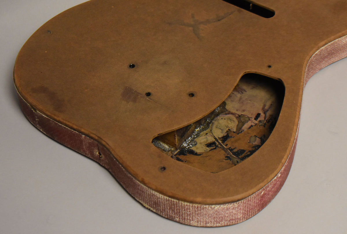 The lower body section shows a brown fiberboard top with a large control cavity revealing worn gold and black foil.