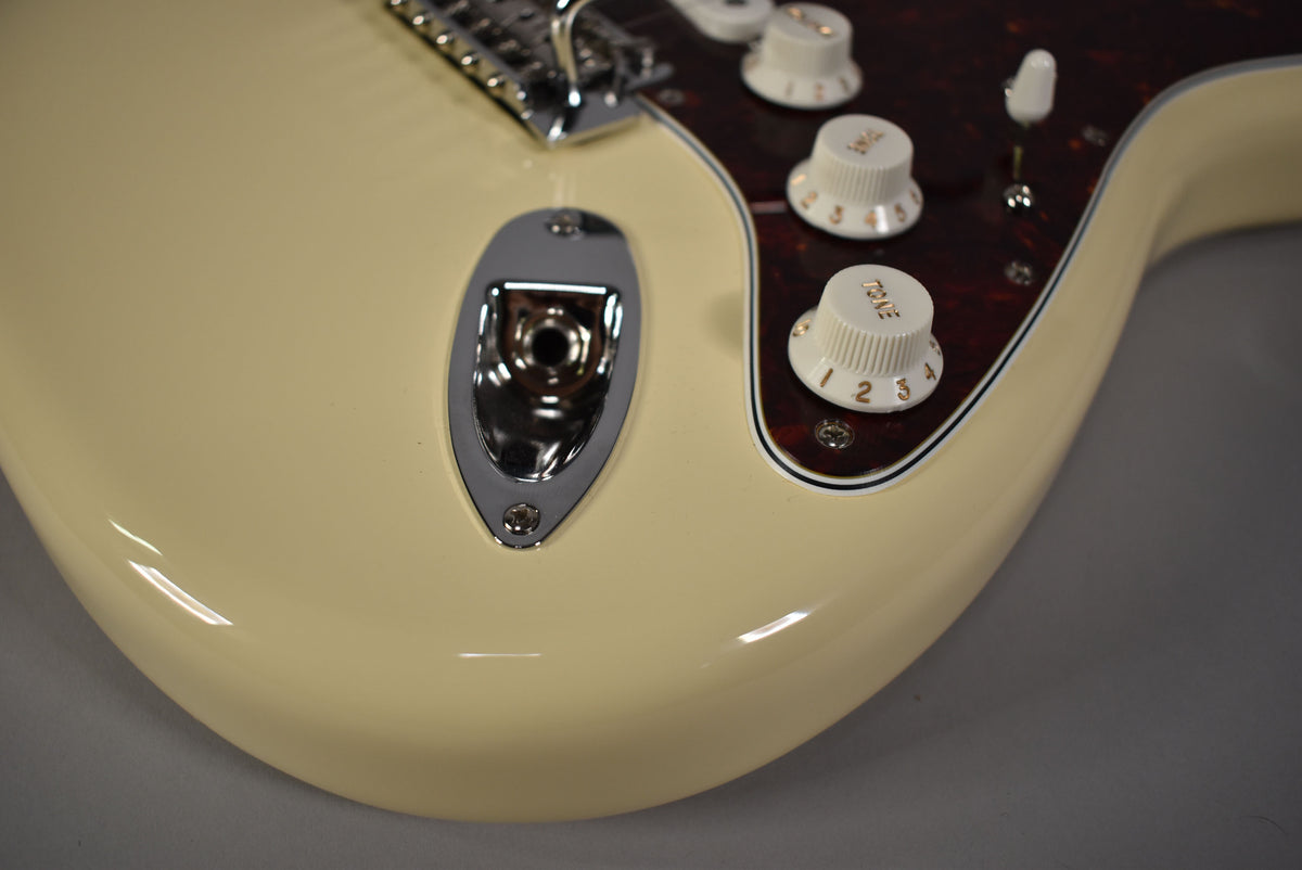 Close-up of the lower bout, showing the glossy Olympic White finish, chrome output jack, and three cream control knobs on a tortoiseshell pickguard.