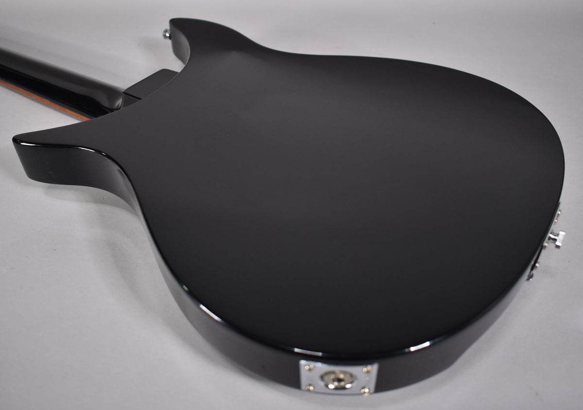 The back of a black guitar, with a chrome output jack at the bottom and a strap button at the top.