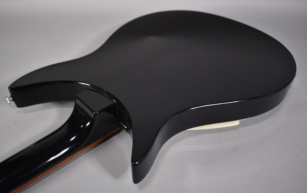 The back of a glossy black guitar body with a neck joint and part of the neck visible, against a light gray background.