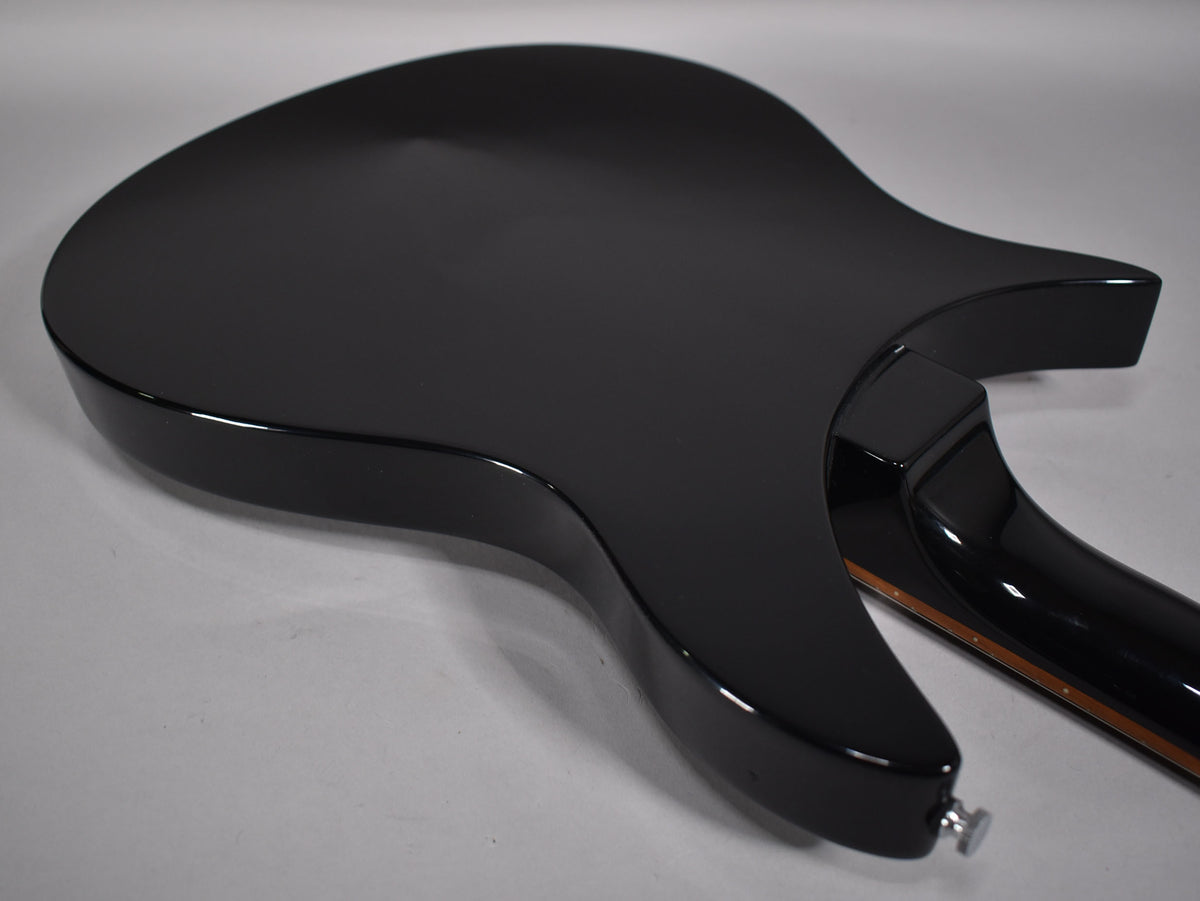 The back of a glossy black guitar, showing the body, neck joint, and part of the neck with a strap button.