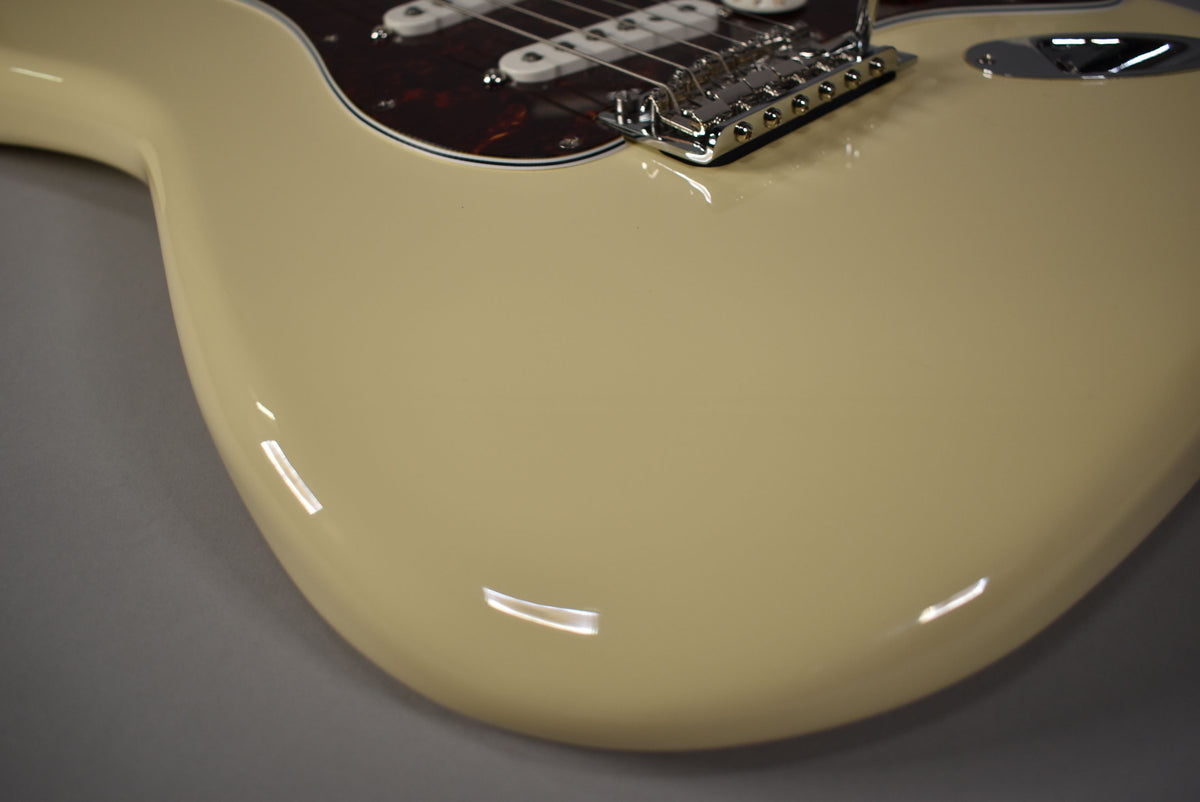 Close-up of the Olympic White Stratocaster's lower body, showing the glossy finish, chrome tremolo bridge, and tortoiseshell pickguard.