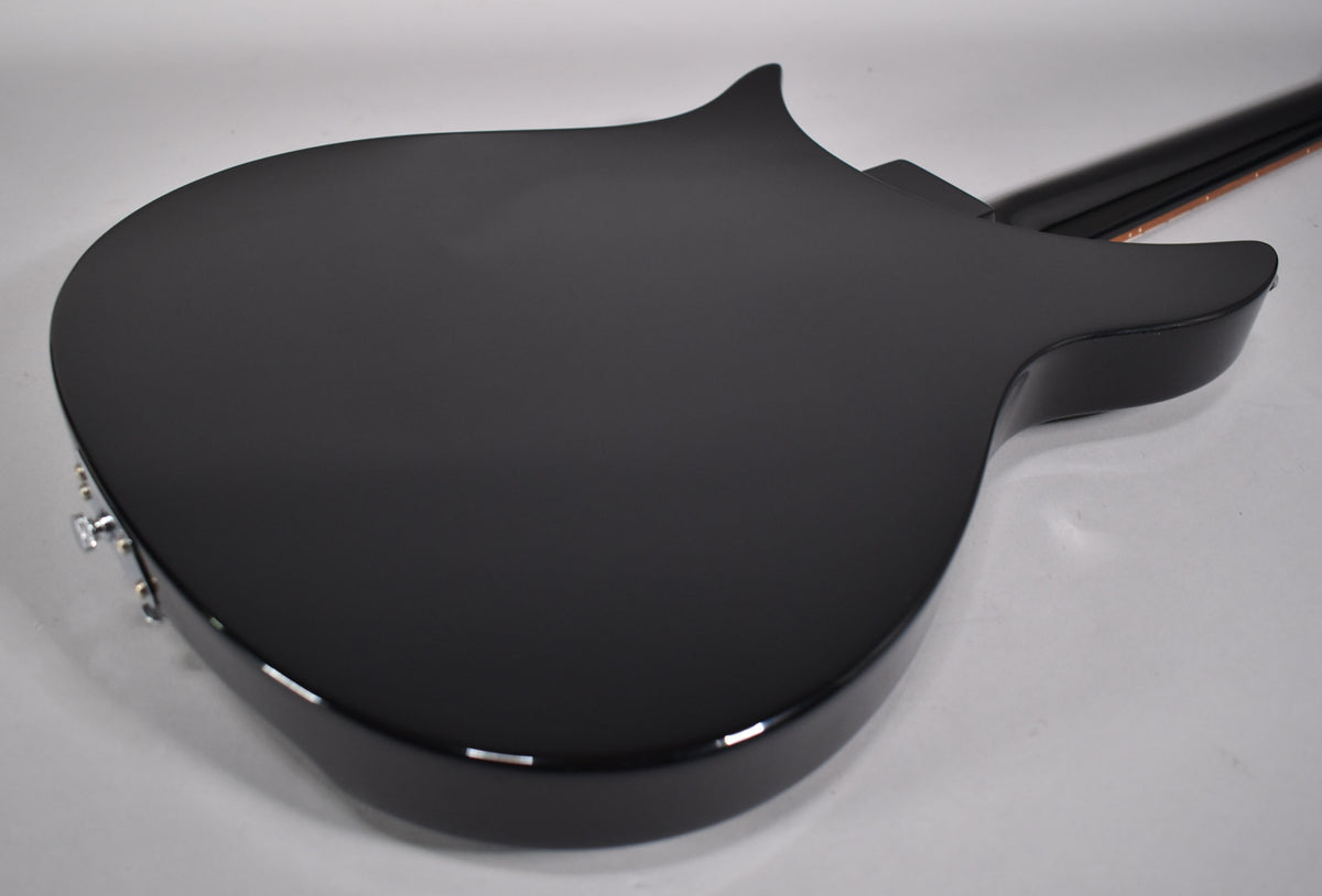The back of a black Rickenbacker guitar, showing the body and part of the neck, with a slight reflection on the lower edge.