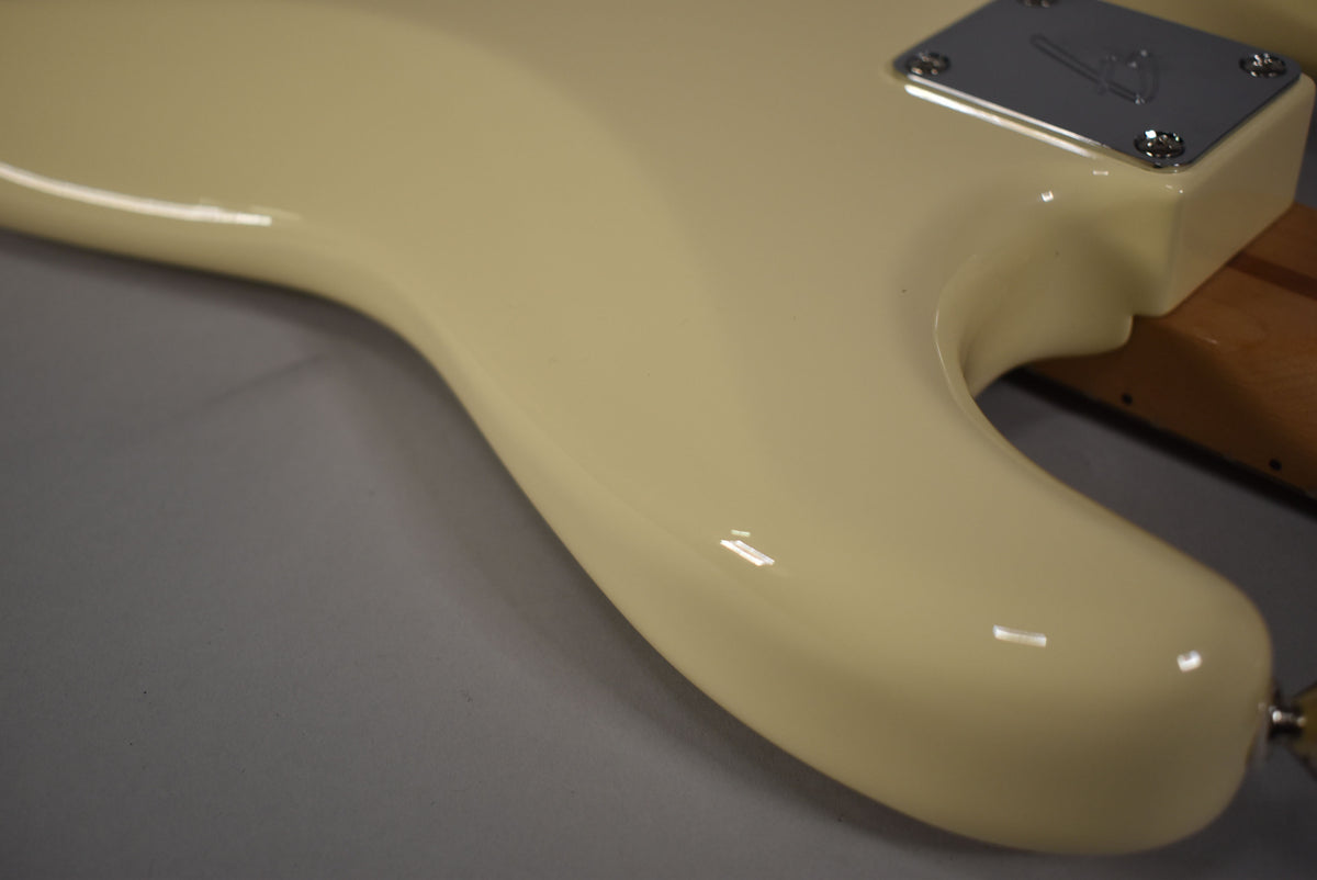 Close-up of the guitar's lower horn and neck joint, showing the glossy Olympic White finish and chrome neck plate.