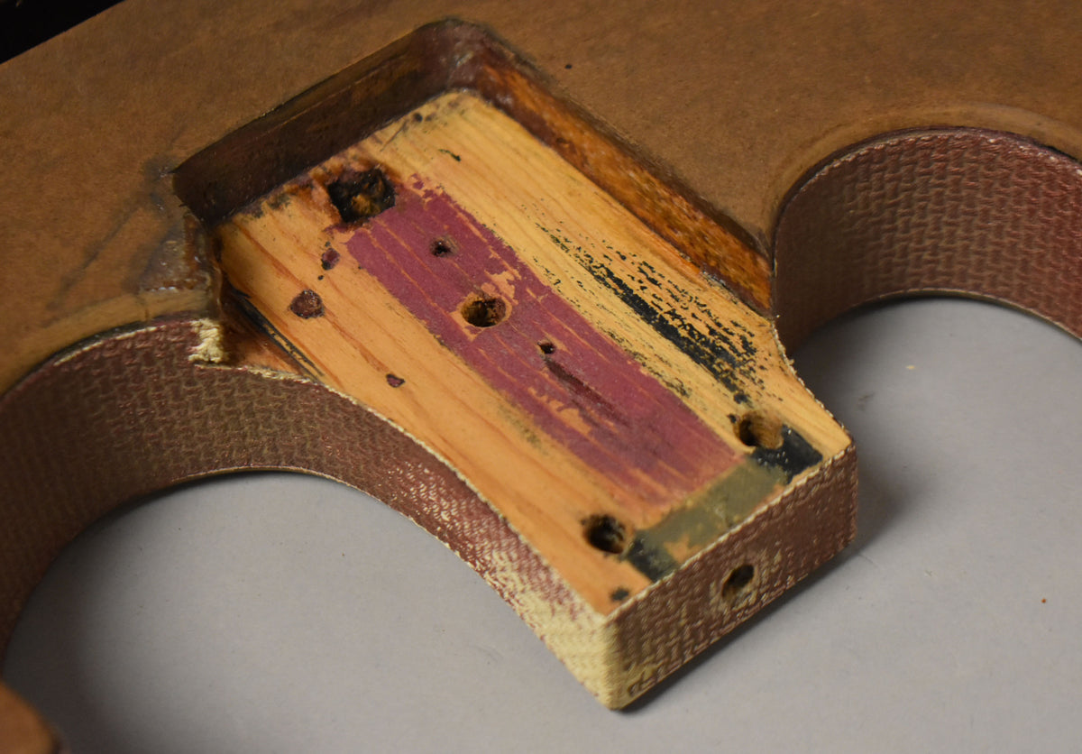 Close-up of the neck pocket, showing exposed wood with remnants of red, black, and yellow paint, and four screw holes.