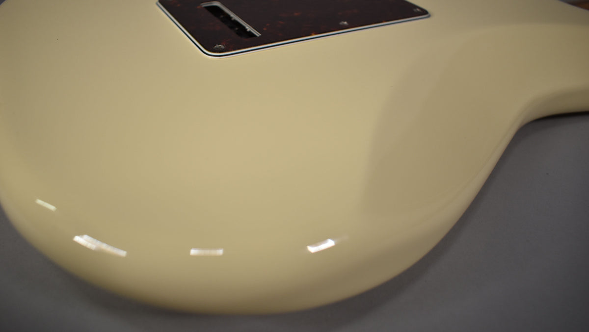 Close-up of the Stratocaster's Olympic White body, showing the lower bout and a portion of the tortoiseshell tremolo cover.