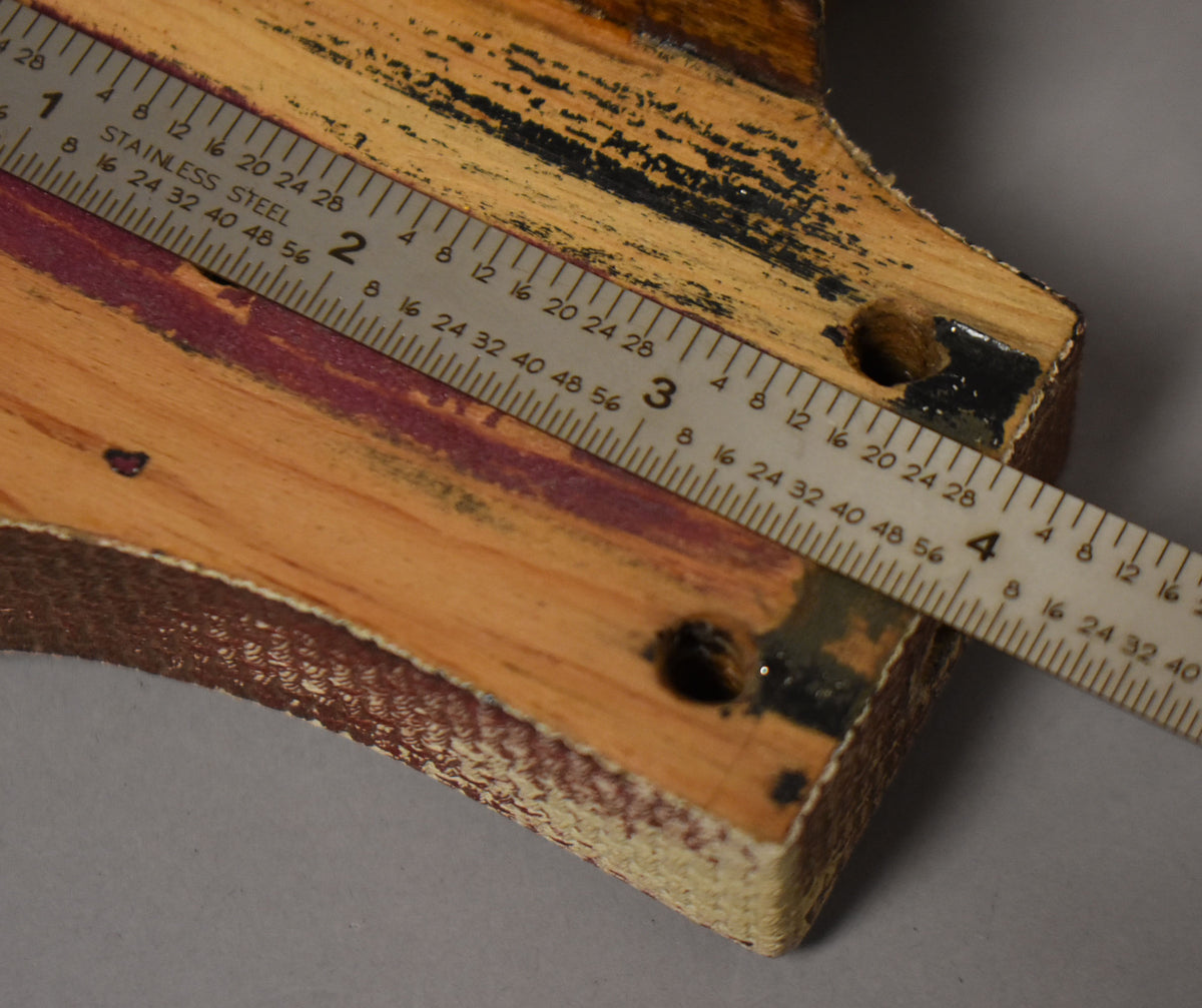 Close-up of the body's neck pocket, showing exposed wood, black paint remnants, two screw holes, and a ruler for scale.